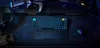 A gaming setup with a keyboard, mouse, headphones, and a handheld console on a desk. Produktbild-Vorschau