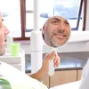 A man is looking in a handheld mirror, likely at a dentist's office. Produktbild-Vorschau