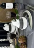 A table setting with a bottle of wine, wine glasses, bowls, napkins, cutlery, and artichokes. Produktbild-Vorschau