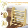 A wooden climbing triangle and ladder for children, shown in a room with a wooden floor and a white wall. Inset images show how the product folds and a close-up of the folding mechanism. Produktbild-Vorschau