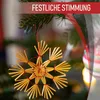 A straw star ornament hanging on a Christmas tree with festive text overlay. Produktbild-Vorschau