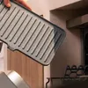 A hand holding a grill plate over a grill. Voir les images du produit