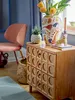 A vase with flowers and a small plant on a wooden cabinet next to a chair. Náhled obrázku produktu