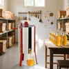 A honey extractor is shown in a workshop or storage area, with shelves of beehives in the background and bottles of honey on a table. Produktbild-Vorschau