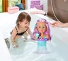 A young child plays in a bathtub with a styling head doll. Voir les images du produit