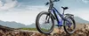 A blue electric mountain bike is parked on rocky terrain with mountains in the background. Produktbild-Vorschau