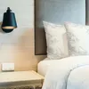 A close-up view of a bed with pillows and a bedside lamp. Anteprima dell’immagine prodotto