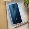A transparent phone case is shown on a white surface, with a pen and a plant in the background. Podgląd zdjęcia produktu