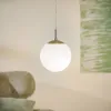 A pendant light hangs in a room with a sofa and a painting in the background. Náhľad obrázku produktu