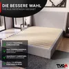 A bed frame with a slatted base is shown in a room setting, with marketing text overlays highlighting its features. Produktbild-Vorschau
