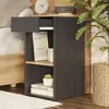 A bedside table with books and a plant next to a bed. Náhled obrázku produktu