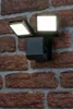 A black LED floodlight with a motion sensor is mounted on a brick wall. Podgląd zdjęcia produktu