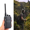 A split image showing a walkie-talkie in a hand on the left and a hiker in a natural environment on the right. Anteprima dell’immagine prodotto