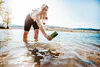 A person is standing in a lake, holding a water purifier and a water bottle. Produktbild-Vorschau