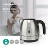 A woman holding a mug is in the background, while a stainless steel electric kettle is in the foreground. Anteprima dell’immagine prodotto