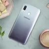 A Samsung Galaxy A40 phone is shown on a marble-like surface, with a small bowl of colorful candies and a cup of coffee nearby. Náhled obrázku produktu