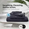 A stack of gray towels on a white surface with a plant in the background. Produktbild-Vorschau