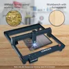 A laser engraving machine with a honeycomb working table is shown on a wooden surface. The image highlights the difference between a workbench with and without a honeycomb table. Náhled obrázku produktu