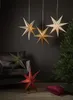 A collection of decorative paper stars are displayed in a room with a sofa and a Christmas tree. Podgląd zdjęcia produktu
