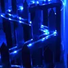 Blue string lights are wrapped around a dark wooden fence. Náhľad obrázku produktu