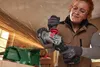 A woman is using an angle grinder to cut metal, with sparks flying. Produktbild-Vorschau