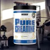 A product shot of a creatine supplement container in a gym setting. Produktbild-Vorschau