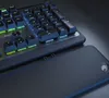 A close-up view of a gaming keyboard with illuminated keys and a wrist rest. Produktbild-Vorschau