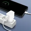 A white Samsung charger and USB-C cable are plugged into a white power strip, with a smartphone charging in the background. Produktbild-Vorschau