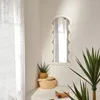 A decorative mirror is displayed on a wall in a room with plants and a woven basket. Náhľad obrázku produktu