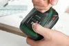 A close-up shot of a person's hands holding a black and green battery pack for a power tool. The battery pack has indicator lights and buttons. Náhľad obrázku produktu