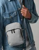 A person wearing a denim jacket and a gray crossbody bag. Anteprima dell’immagine prodotto