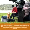 A man and his dog are preparing for a camping trip next to an open car. Produktbild-Vorschau