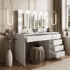 A modern white vanity table with a lighted mirror, drawers, and a stool in a well-lit room. Náhled obrázku produktu