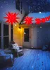 A string of red star-shaped lights hangs across a snowy porch at night, with chairs visible. Produktbild-Vorschau
