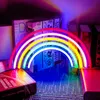 A neon rainbow light is displayed on a shelf with books. Produktbild-Vorschau