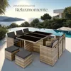A rattan dining set with black cushions is placed on a patio overlooking a scenic ocean view with a swimming pool. Náhled obrázku produktu