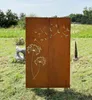 A rusty metal garden screen with a dandelion motif is placed in a grassy outdoor area with trees and sculptures in the background. Produktbild-Vorschau