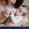 A mother is feeding her baby with a baby bottle. Produktbild-Vorschau