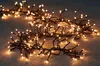A string of warm white fairy lights with black wires is laid out on a wooden surface. Produktbild-Vorschau