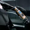 A hand wearing a black glove sprays a product onto a car's trim. Produktbild-Vorschau