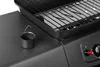 A close-up view of a black gas grill, focusing on a small cup with a handle and the grill grates. Produktbild-Vorschau