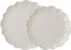 Two white scalloped plates with embossed festive designs. Produktbild-Vorschau