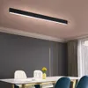 A modern dining room with a long LED ceiling light above a table with chairs and a vase of yellow flowers. Náhľad obrázku produktu