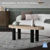 A modern living room scene featuring a coffee table with black legs and a light wood top, placed on a patterned rug in front of a sofa. Podgląd zdjęcia produktu