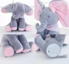 Grauer Plüsch-Elefant mit rosa Innenohren und Füßen, mit rosa gepunktetem Schal, aus mehreren Blickwinkeln gezeigt, einschließlich einer Ansicht seines Batteriefachs Voir les images du produit