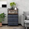 A fabric dresser with drawers and shelves is placed next to a sofa in a room with a concrete wall. Náhled obrázku produktu