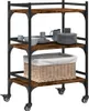 A three-tier kitchen cart with a rustic wood finish and black metal frame, shown with some dishes and a basket. Náhľad obrázku produktu