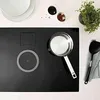 A top-down view of a modern induction cooktop with a saucepan and a spatula. Produktbild-Vorschau