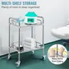 A stainless steel rolling cart with multiple shelves, holding medical supplies and towels, in what appears to be a clinic or laboratory setting. Produktbild-Vorschau