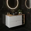 A modern bathroom vanity with a black sink and gold faucet against a black marble tiled wall. Anteprima dell’immagine prodotto